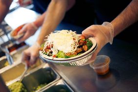 An employee prepares a burrito bowl at a Chipotle location