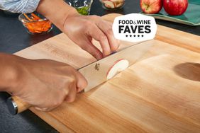 Chef knife cutting an apple on a wooden cutting board
