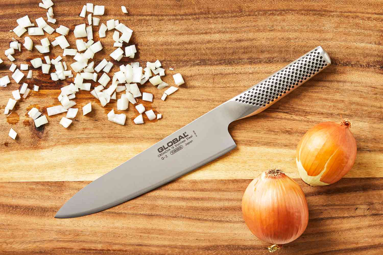 Global 8-Inch Chef's Knife on a wooden cutting board with diced and whole onions