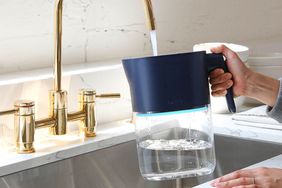 Hands holding a water filter pitcher under a running sink