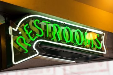 A neon "restrooms" sign at a restaurant