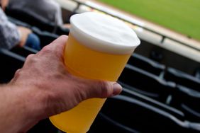 A person holds a beer in a stadium