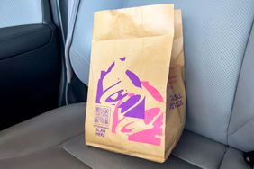 A Taco Bell fast food bag on the passenger seat of a car
