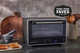 KitchenAid Digital Countertop Oven sitting on a black countertop next to kitchen utensils